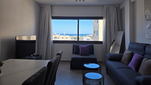 Una sala de estar moderna con un ventanal grande, una zona de comedor y un sofá.