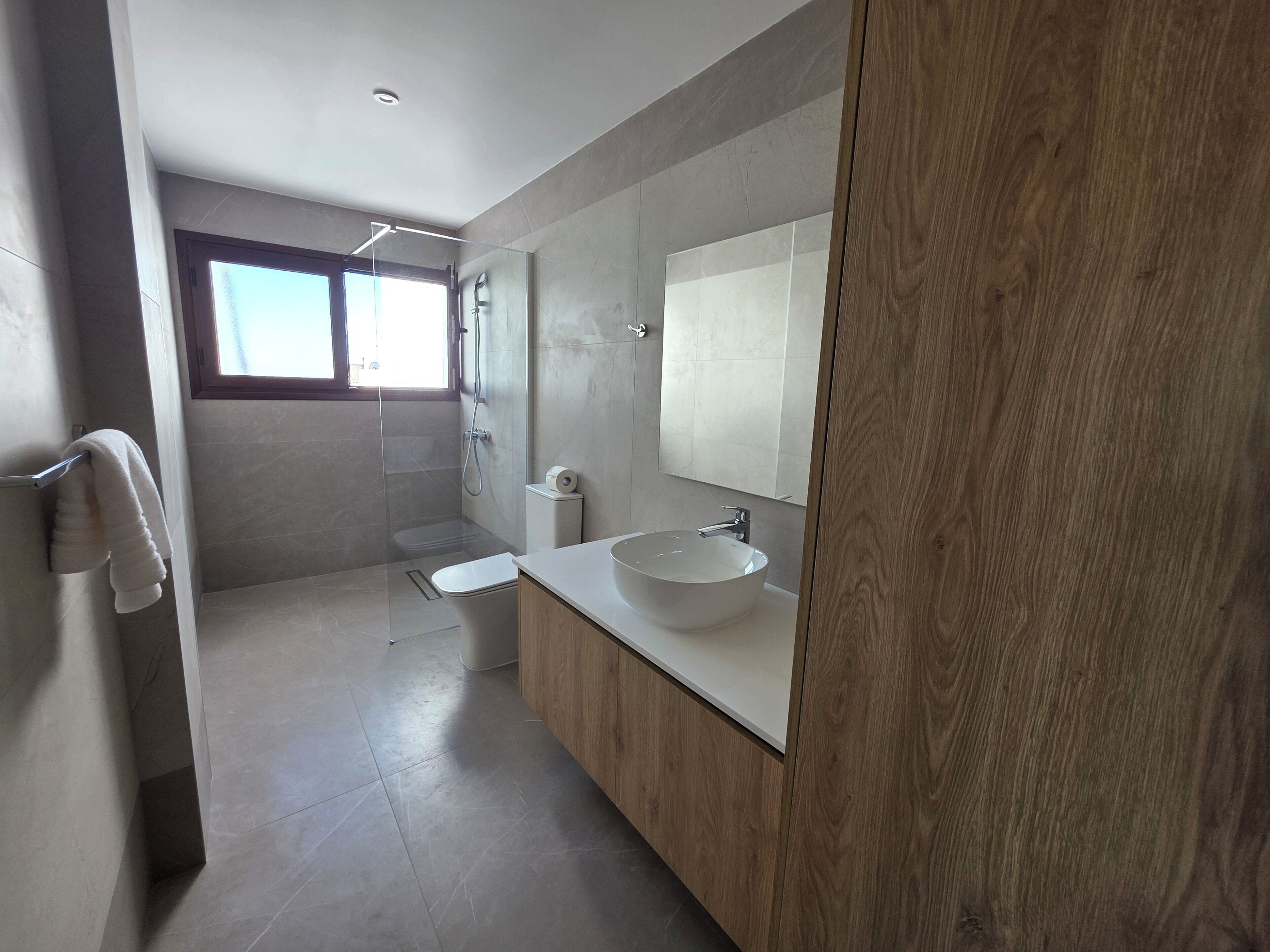 A modern bathroom with a large mirror, a white sink, and a shower.