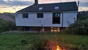Una casa con techo de tejas, una chimenea y un ventanal pequeño.