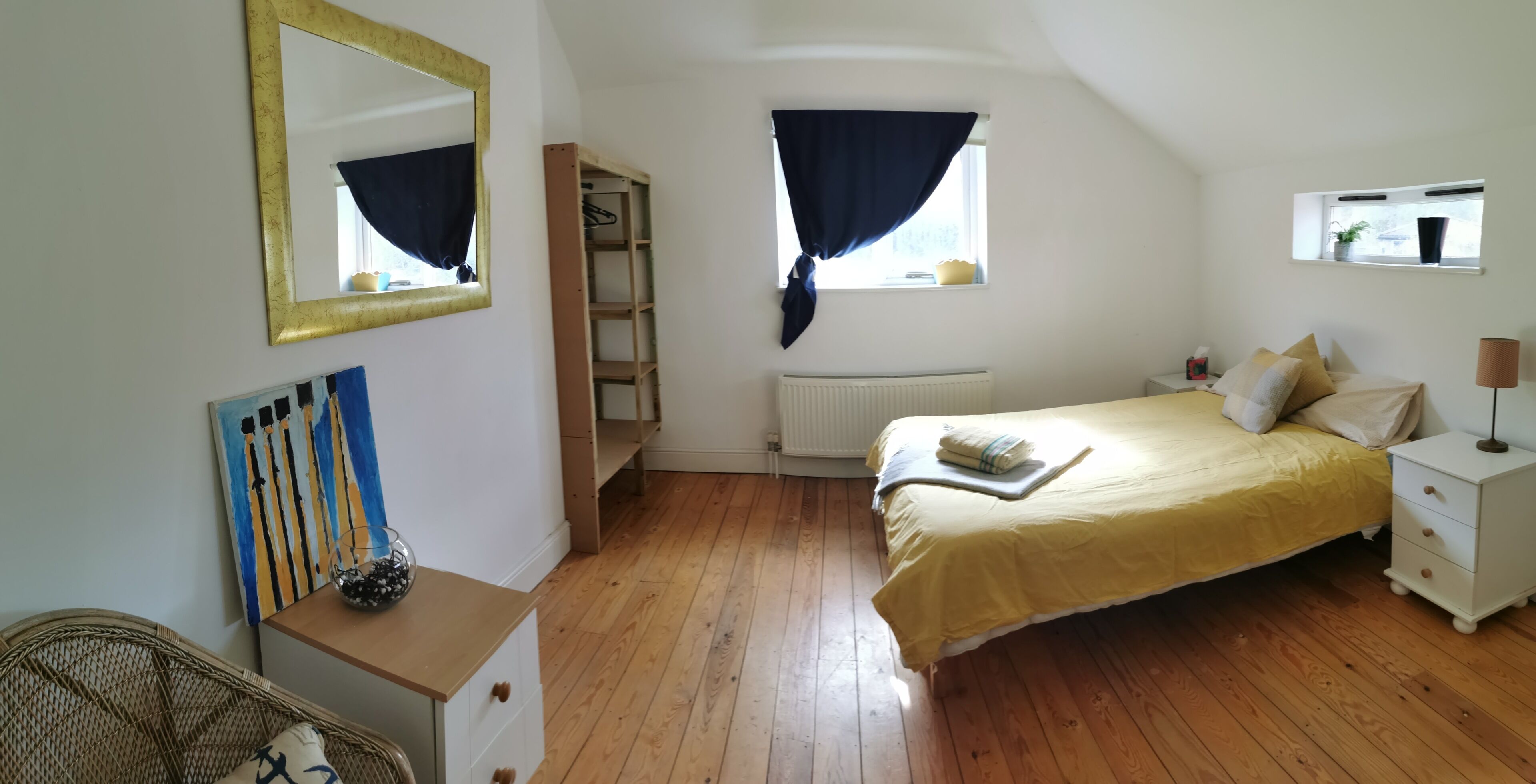 Une chambre à coucher avec un lit, une table de chevet, une commode et une fenêtre avec des rideaux.