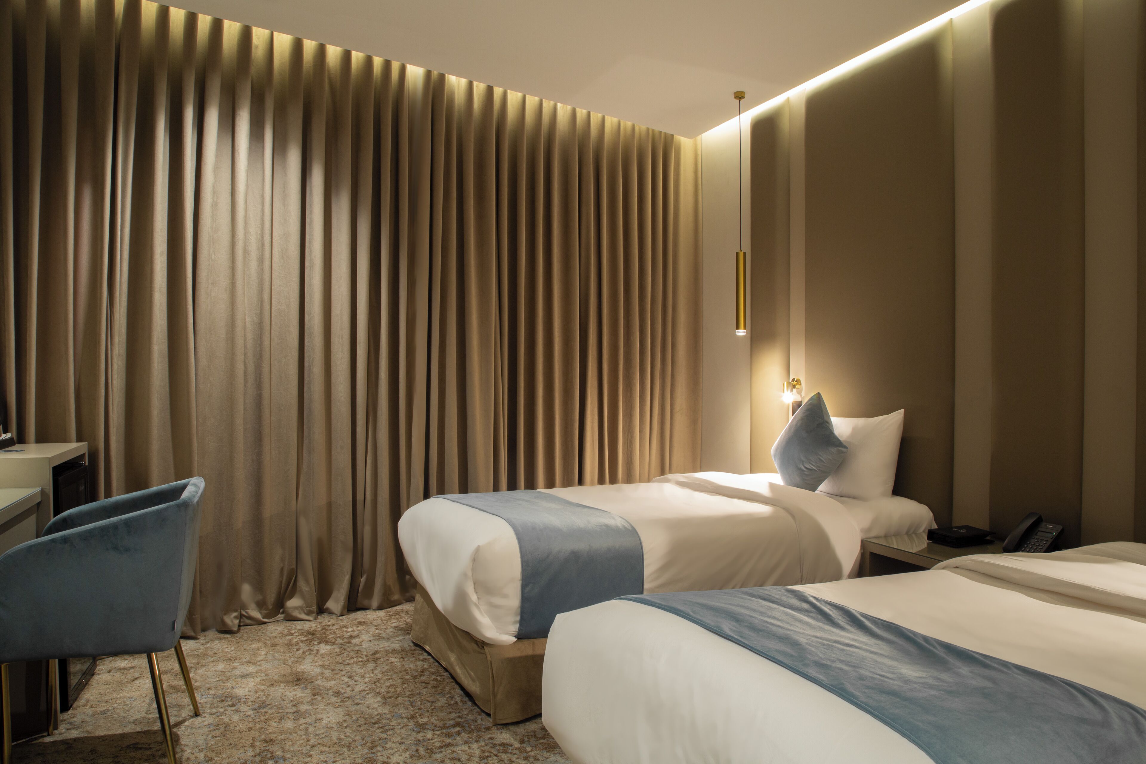 A hotel room with two beds, a desk, and a chair.