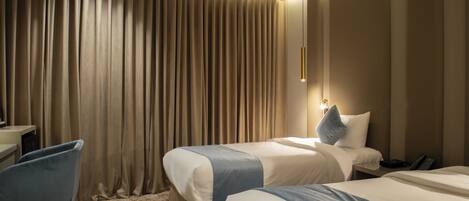 Hotellihuone, jossa on kaksi sänkyä, työpöytä ja tuoli.