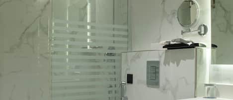 Un baño moderno con ducha de vidrio, inodoro blanco y encimera de mármol.