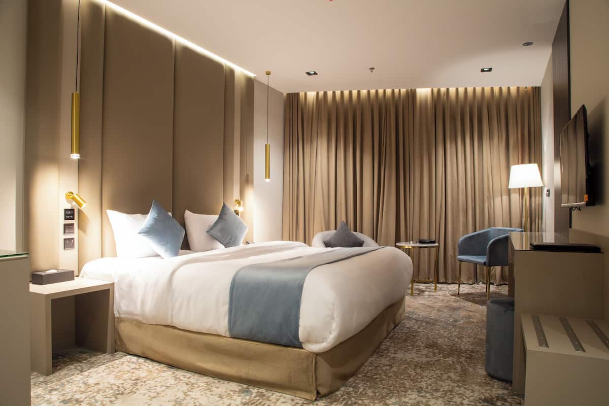 A modern hotel room with a large bed, bedside tables, a desk, and a chair.