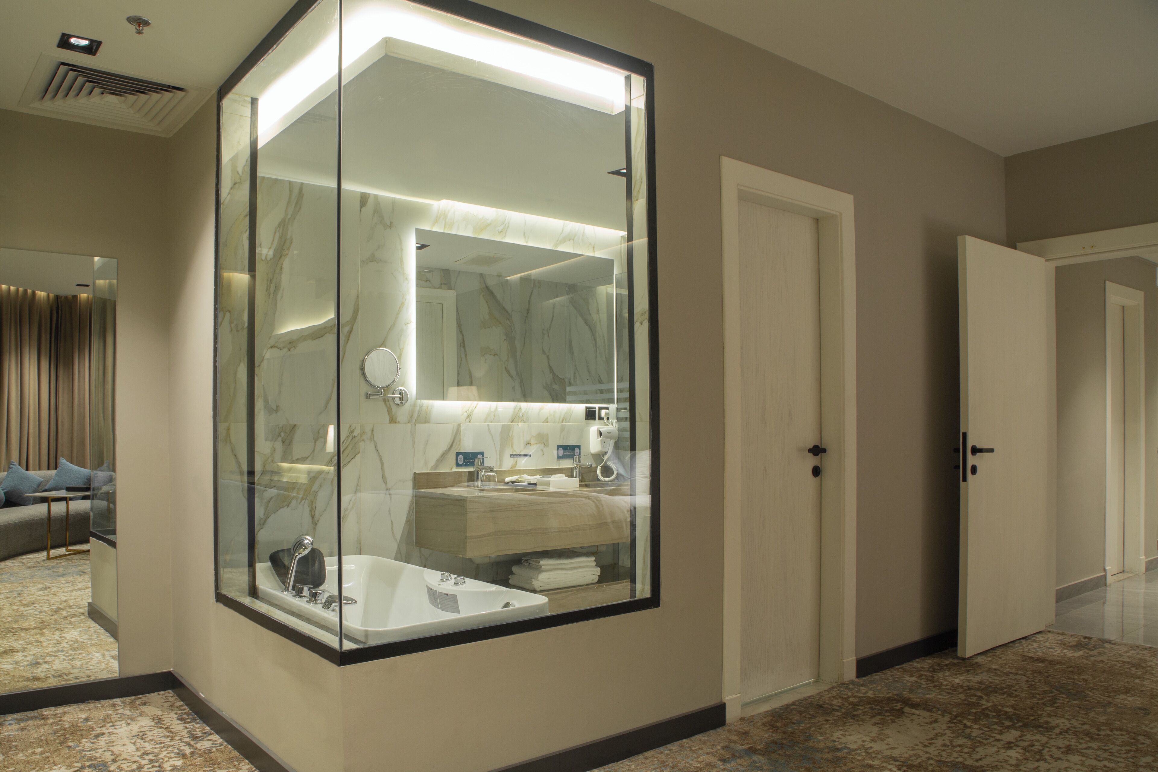 Un baño moderno con tocador con cerramiento de vidrio, salpicadero de mármol y cabina de ducha independiente.