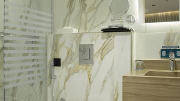 Une salle de bain moderne avec une douche à parois de verre, un mur en marbre, un meuble-lavabo en bois et des toilettes.