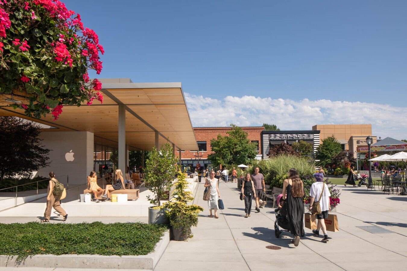 Un espacio comercial al aire libre con un edificio moderno, zonas de estar y diversas tiendas.