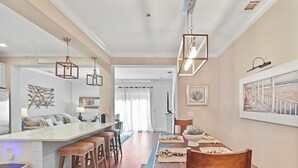 A modern kitchen with a central island, wooden bar stools, and pendant lighting. - Beautiful Reserve Townhouse - FLETC Welcome! (Saint Simons Island)
