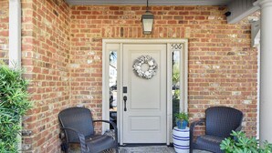 A brick exterior with a white door, two wicker chairs, and a potted plant. - Beautiful Reserve Townhouse - FLETC Welcome! (Saint Simons Island)