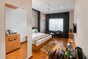 A hotel room with a bed, wooden wardrobe, desk, chair, and a television. - Xenious Micro  (Amritsar)