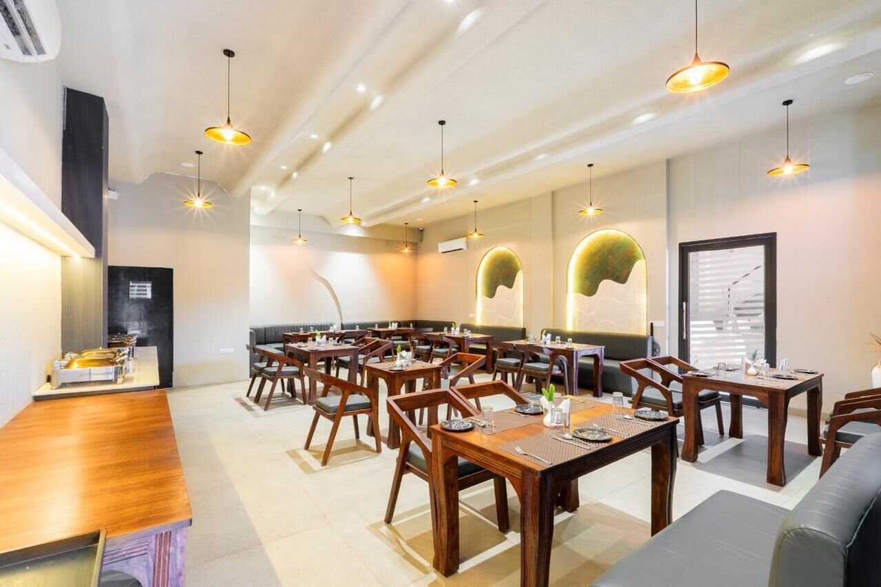 Un restaurante con varias mesas y sillas de madera, iluminación colgante y una decoración interior moderna.