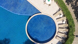 An aerial view of a circular pool with a surrounding patio area, including seating and a small table. - Bz44 200 metros da praia Área Gourmet (Buzios)