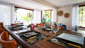 A dining area with a long wooden table set for a meal, surrounded by chairs. - Bz44 200 metros da praia Área Gourmet (Buzios)