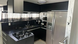 Una cocina compacta con estufa a gas, electrodomésticos de acero inoxidable y salpicadero de mármol.