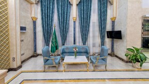 A luxurious room with a sofa set, a coffee table, and a flag. - Alfursan Almotahida Hotel (Jeddah)