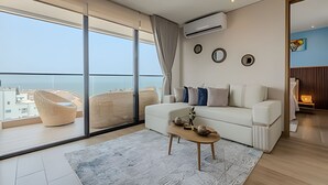 Una sala de estar moderna con un ventanal grande, un sofá blanco y una pequeña mesa de madera.