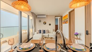 Una habitación de hotel moderna con balcón, un comedor con una mesa para dos, y una cama con vistas.