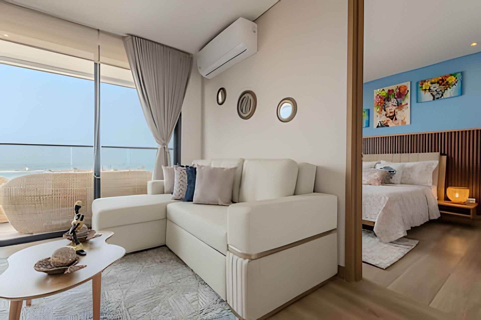 A modern bedroom with a large window, a sofa, a bed, and a small table with decorative items.