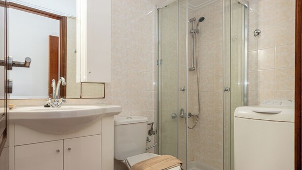 A bathroom with a glass-enclosed shower, a sink, and a toilet. - Cielo Chania II (Chania)
