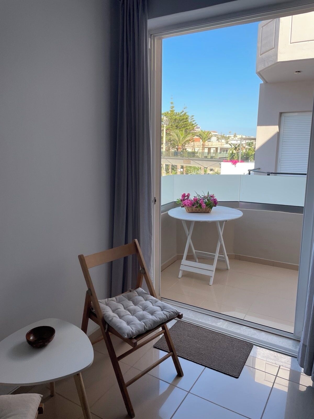 Ein Balkon mit einem Holzbalkon, einem kleinen runden Tisch und einem Blumentopf.