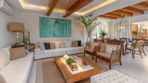 Una sala moderna con un sofá blanco, una mesa de centro de madera y sillas de mimbre.