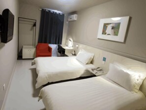 Habitación de hotel con dos camas, un escritorio, una silla, un televisor y un cuadro en la pared.