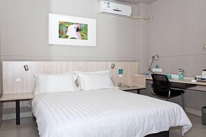 Una habitación de hotel con cama, mesita de noche, escritorio, silla y un cuadro en la pared.