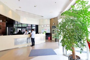 Un área de recepción con mostrador, una planta en maceta grande y un ventanal.