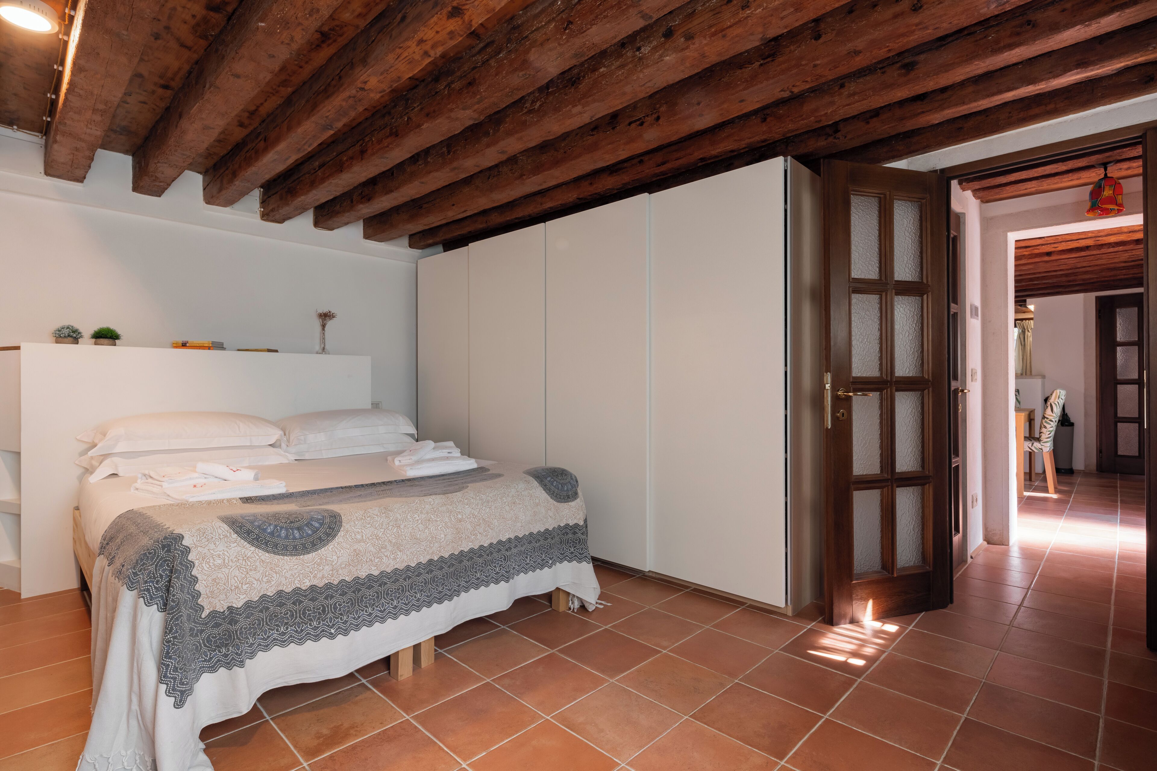 A bedroom with a bed, a wardrobe, and a door leading to another room.