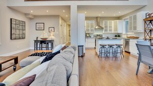 A spacious living area with a sofa, a dining table, and a kitchen in the background. - EXECUTIVE WATERFRONT LIVING AT ITS FINEST!!! WELCOME to this immaculate home! (Wasaga Beach)