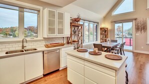 A modern kitchen with a central island, large windows, and a dining area with a view. - EXECUTIVE WATERFRONT LIVING AT ITS FINEST!!! WELCOME to this immaculate home! (Wasaga Beach)