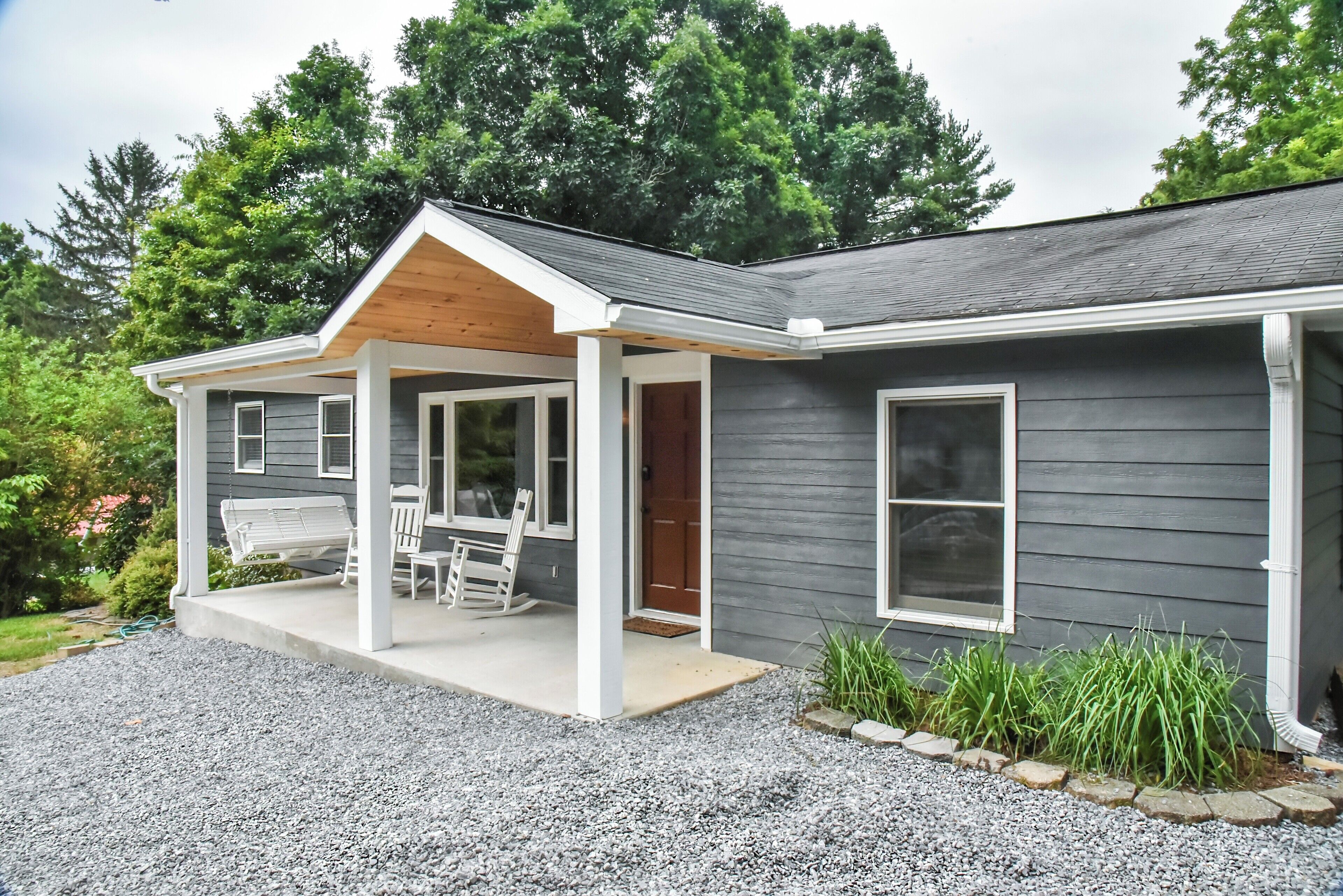 A two-story house with a covered porch, a front door, and a small garden area.