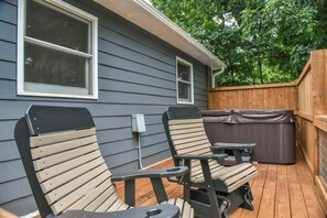 Une terrasse extérieure avec deux chaises en bois et une table, un jacuzzi et une clôture en bois.