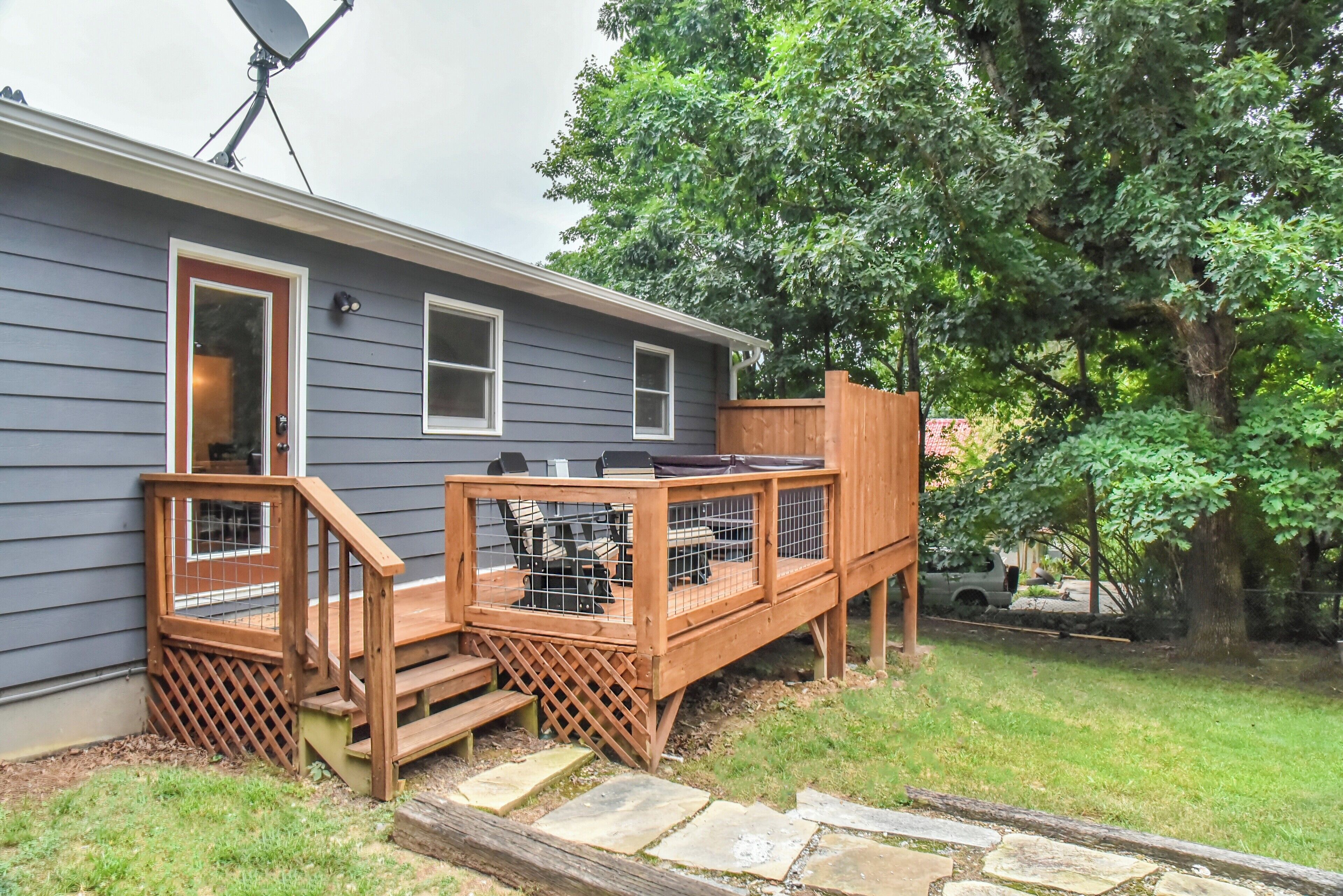 A house with a deck, a satellite dish, and a vehicle in the background.