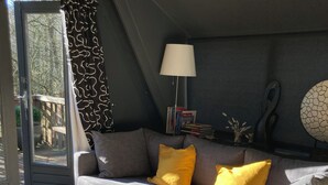 A grey sofa with yellow cushions, a floor lamp, and a wall-mounted abstract art piece in a modern living room. - Chalet Séquoia 138, Chalet Durbuy Family, nature, swimming pool dogs welcome (Durbuy)