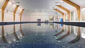 A swimming pool with a tiled floor, wooden beams, and large windows. - Chalet Séquoia 138, Chalet Durbuy Family, nature, swimming pool dogs welcome (Durbuy)