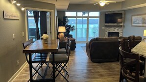 A spacious living area with a dining table, sofa, and a TV mounted on the wall. -  2110 Towers Beautiful Condo! Quiet! Elevators, indoor/outdoor pools. Free Wifi (Osage Beach)