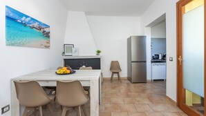 A compact kitchen with a refrigerator, microwave, and white cabinets.