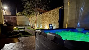 An outdoor swimming pool area with a tiled deck, a wooden fence, and a wall with a window.