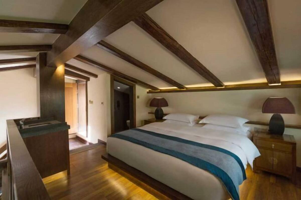 Ein Schlafzimmer mit Bett, Nachttischen, Schreibtisch und einer Tür.