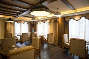 A hotel dining area with multiple tables and chairs, large pendant lights, and curtains. - TianQingSheHotel (Shangri-La)