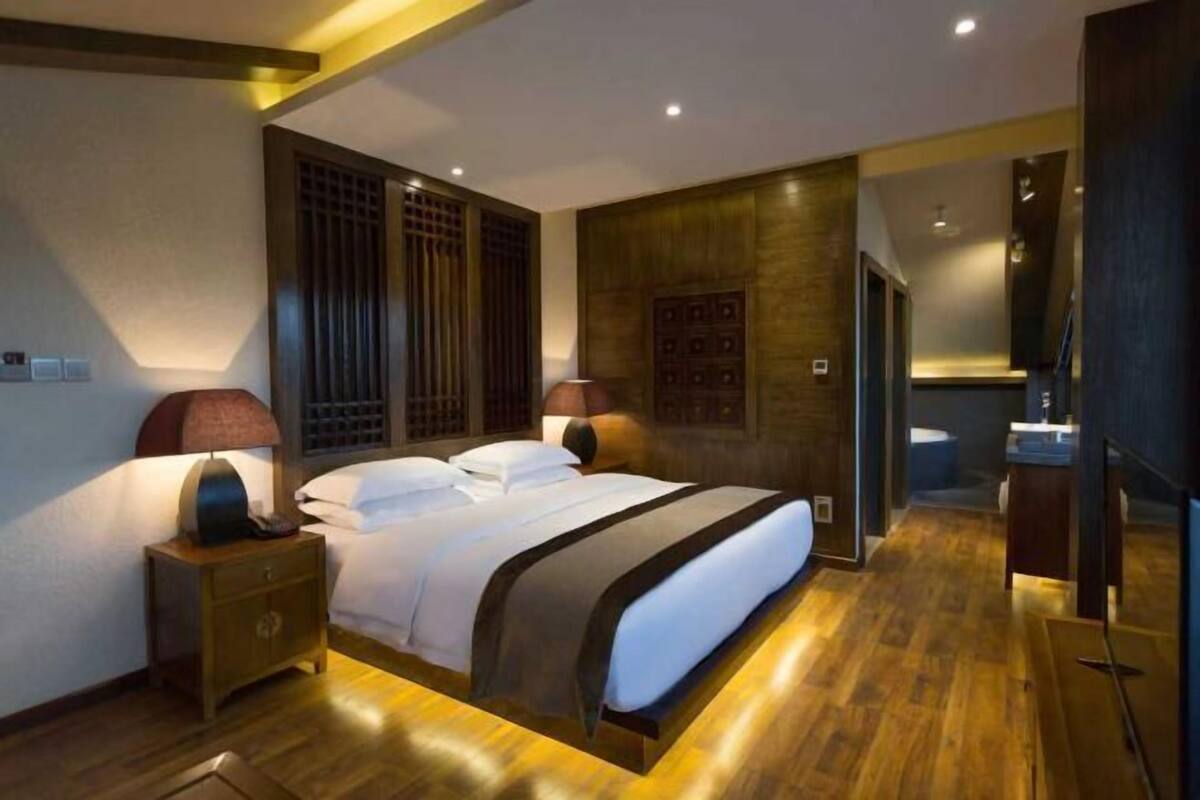 Ein modernes Schlafzimmer mit einem großen Bett, Holzboden und einem Nachttisch mit Lampe.
