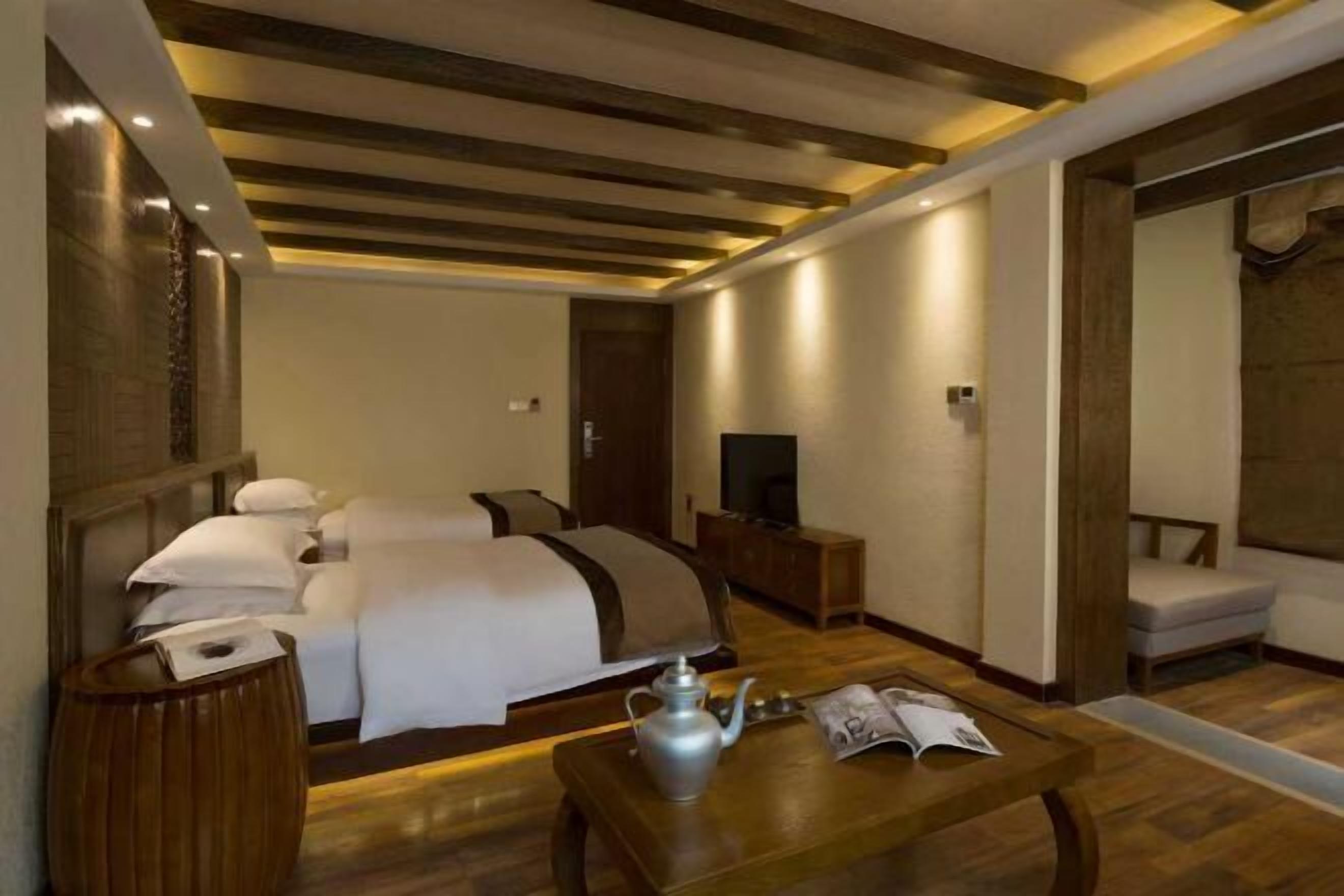 Habitación de hotel con cama, mesita de noche, televisión y zona de estar con sillón y mesa.