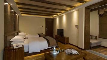 Habitación de hotel con cama, mesita de noche, televisión y zona de estar con sillón y mesa.