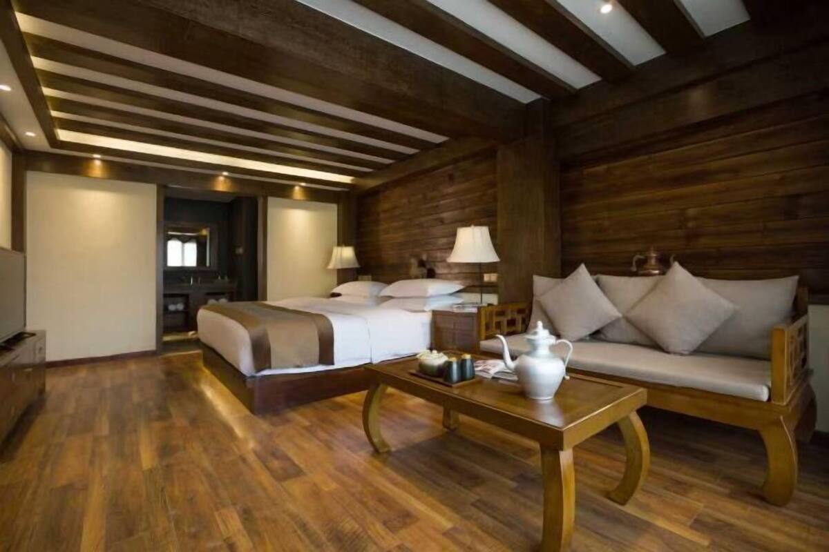 Ein Hotelzimmer mit Holzboden, einem Bett, einem Schlafsofa, einem Couchtisch und einer Lampe.