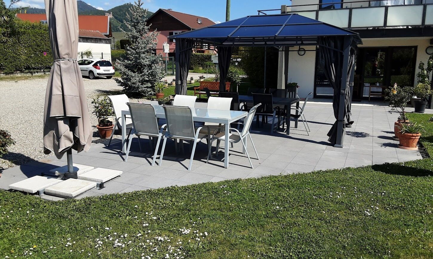 An outdoor patio with tables and chairs, a covered seating area, and potted plants.
