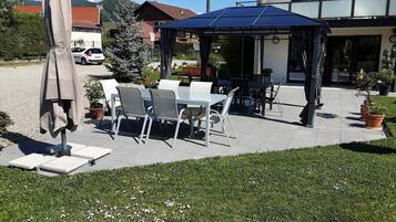 An outdoor patio with tables and chairs, a covered seating area, and potted plants.