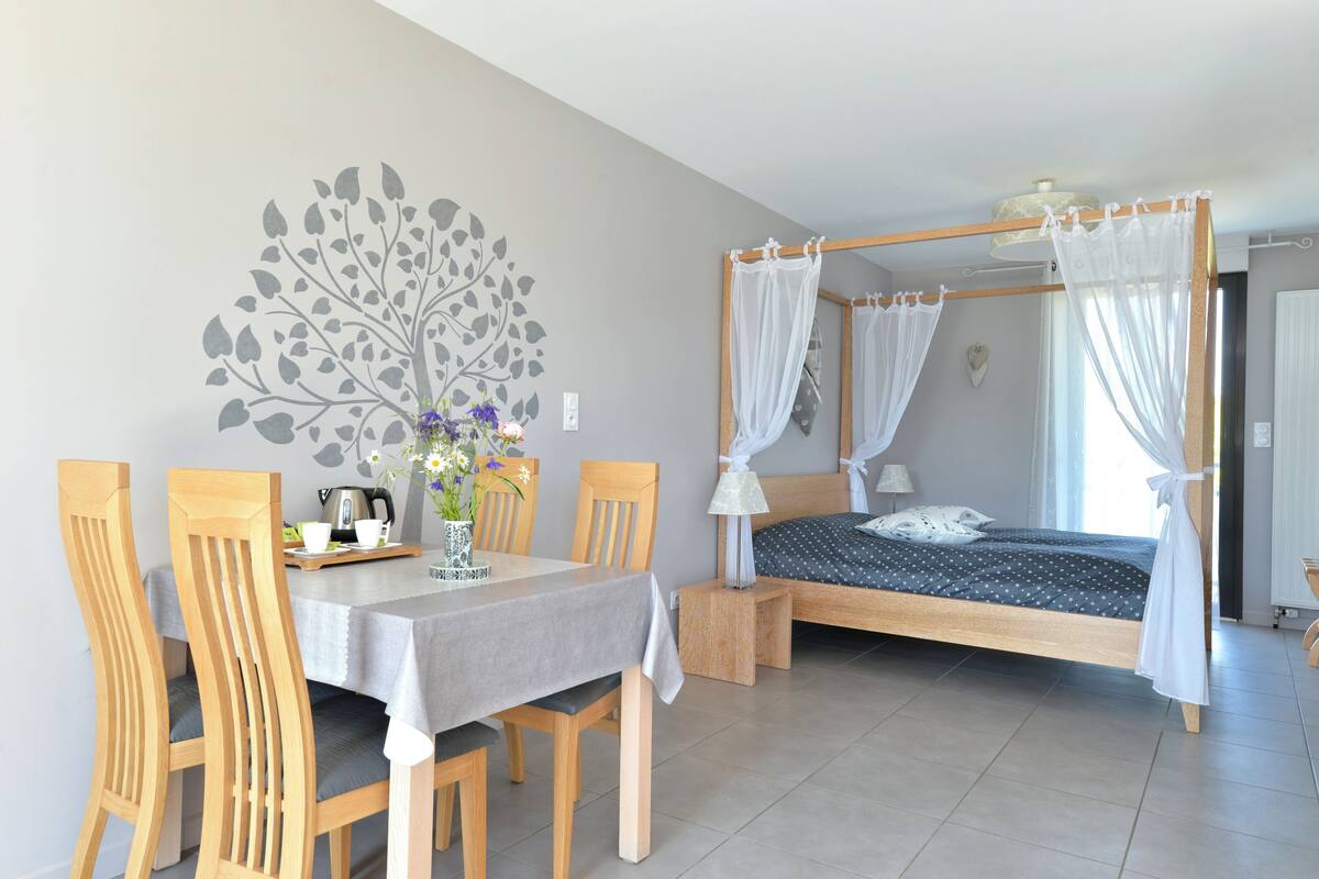 Una camera da letto con un letto a baldacchino, un tavolo da pranzo con sedie e un affresco sulla parete.