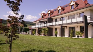 Une maison moderne à deux étages, dotée d’un balcon, d’une pelouse bien entretenue et d’une antenne parabolique sur le toit.