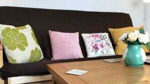 A living room with a dark brown sofa, a wooden coffee table, and a vase with flowers.
